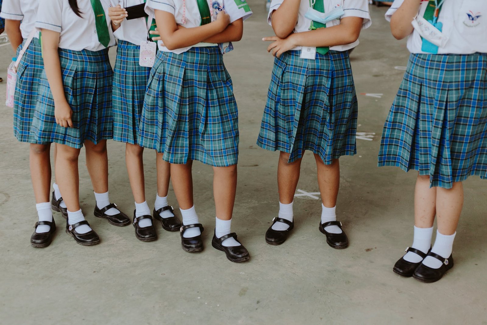 low section of girls in school uniforms standing in school corridor