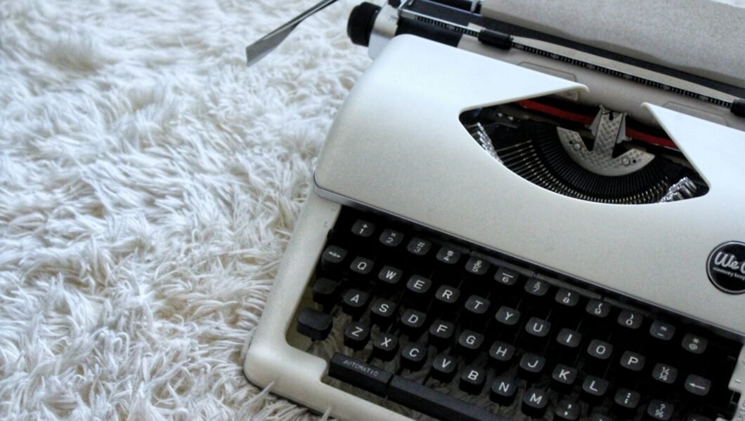 white and black typewriter on white textile